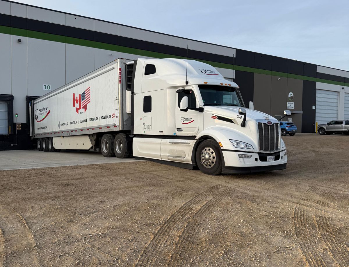 A Fastlane Transport tractor-trailer parked at a distribution warehouse loading dock